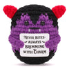 A handmade crochet animal doll with black and purple fur and red ears, featuring a card that reads Never Bites Always Brimmin