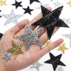 A hand holds several glitter rhinestone star patches of various sizes and colors.