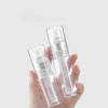 A hand holds a clear refillable fine mist spray bottle for hair and travel.