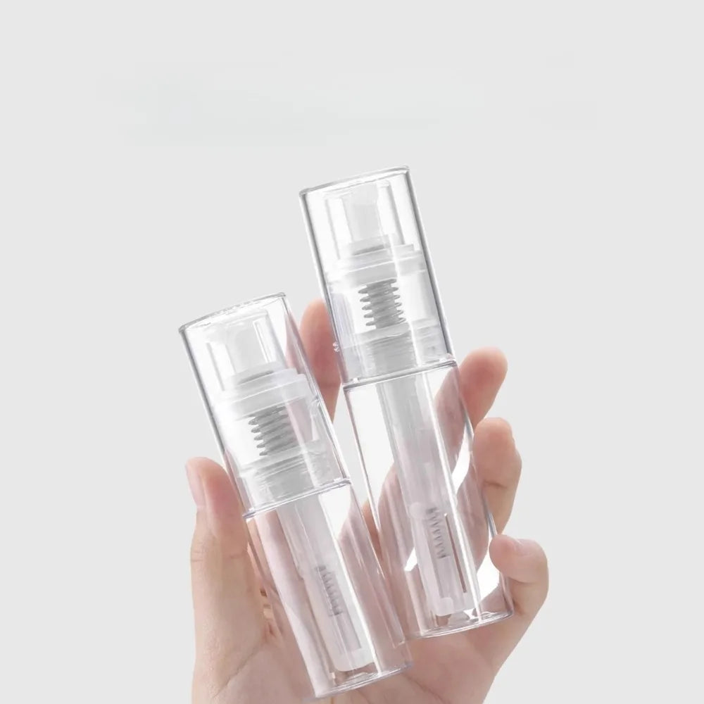 A hand holds a clear refillable fine mist spray bottle for hair and travel.