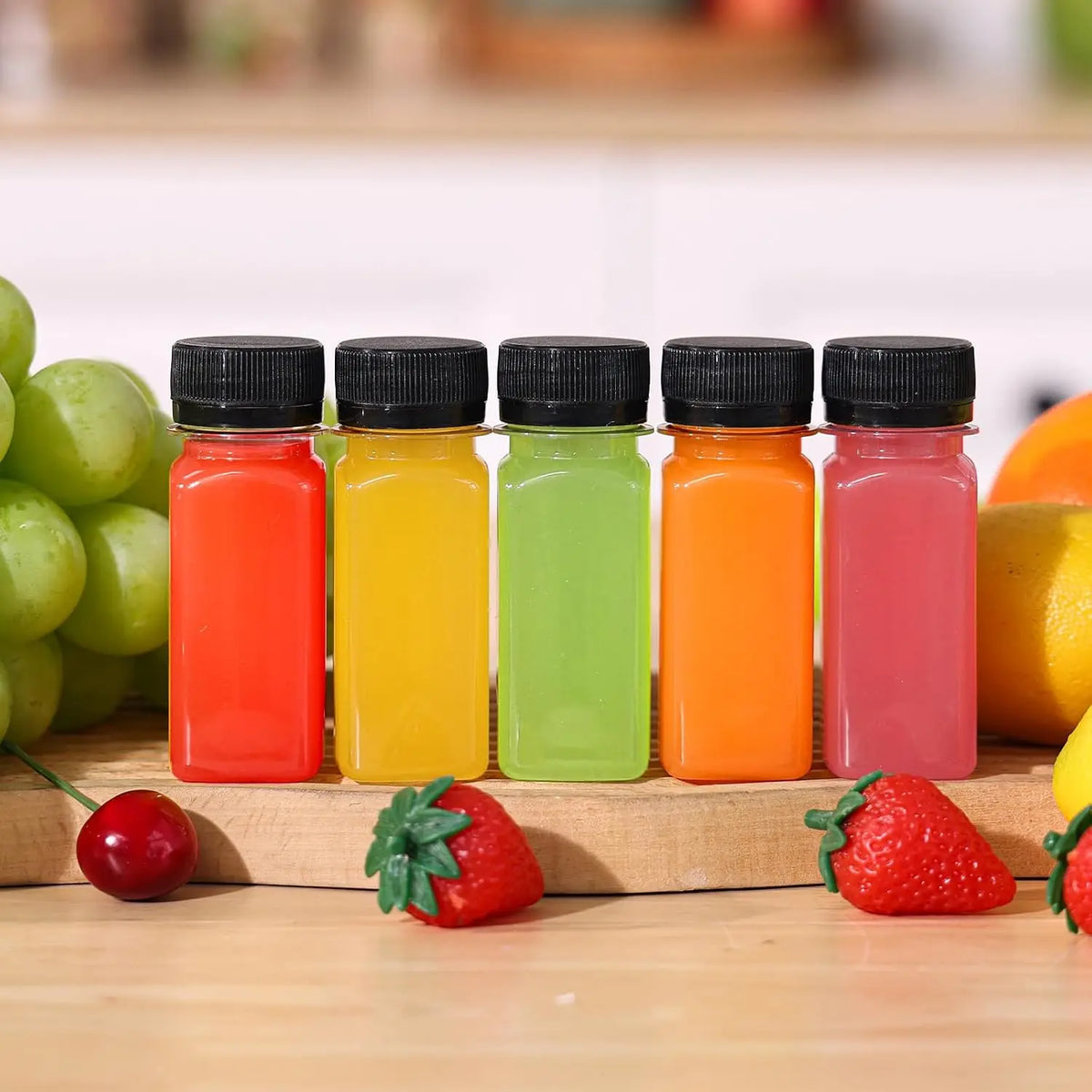 A row of six leak-proof clear plastic juice bottles filled with various fruit juices in bright colors on a wooden surface.