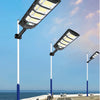 A modern solar street light fixture mounted on a pole, illuminating a paved walkway.