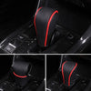 Close-up view of a black leather gear shift knob cover with red accents installed in a vehicle interior.
