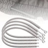 A close-up view of a silver spring drawstring needle threader tool with multiple coiled ends.
