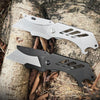 A stainless steel folding utility knife with five replaceable blades is shown resting on a tree trunk amidst dry leaves.
