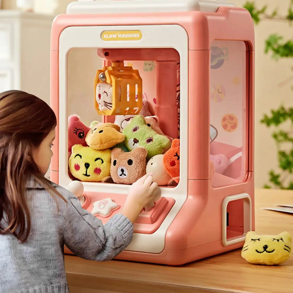 A young girl is interacting with a pink mini claw machine for kids, which features toys and lights.