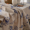 A beige cotton-linen tablecloth featuring a blue rustic fern print, draped on a table.