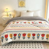 A white and gray plush throw blanket with a floral pattern is displayed on a bed.