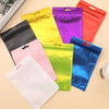 A collection of colorful Mylar ziplock bags in yellow, purple, red, pink, and blue are displayed on a light background.