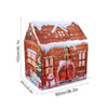 A brown wooden play castle tent with a pitched roof and windows decorated with snow and festive elements.