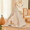 A white foldable play tent with curtains is set up indoors on a wooden floor, featuring a stuffed animal inside.