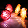 A set of three bright orange LED headlights and spotlights reflecting on a surface.