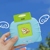 A hand holds a light blue learning toy featuring a cat illustration and a green card labeled cat.
