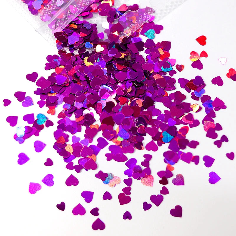 A pile of shiny holographic purple and pink heart-shaped sequins for resin crafts.