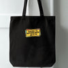 Black tote bag with an embroidered patch that reads There is nothing basic about me