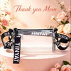 A clear crossbody bag with a black adjustable strap displayed on a pink cake decorated with flowers.