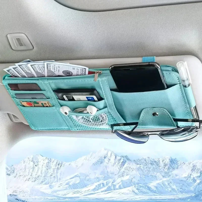 A teal car sun visor organizer holding sunglasses, a smartphone, and various cards in multiple pockets.
