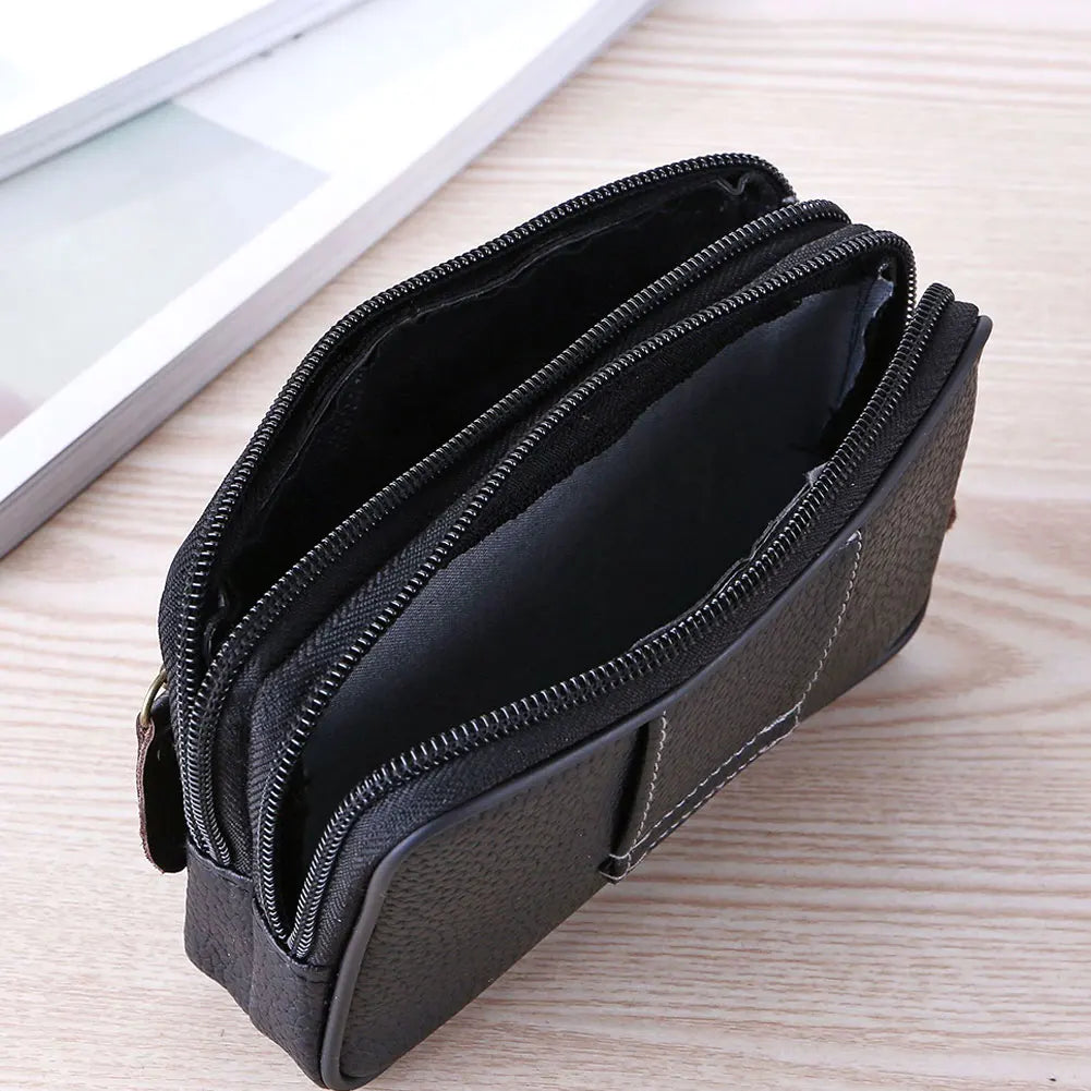 A black men's multi-function PU leather waist bag with zippered compartments resting on a light wooden surface.