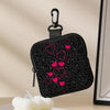 Black mini coin purse with a leopard print and pink heart embroidery hanging from a black clip