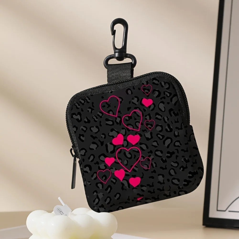 Black mini coin purse with a leopard print and pink heart embroidery hanging from a black clip