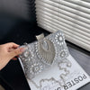 Silver rhinestone evening clutch with a chain strap resting on a white surface.
