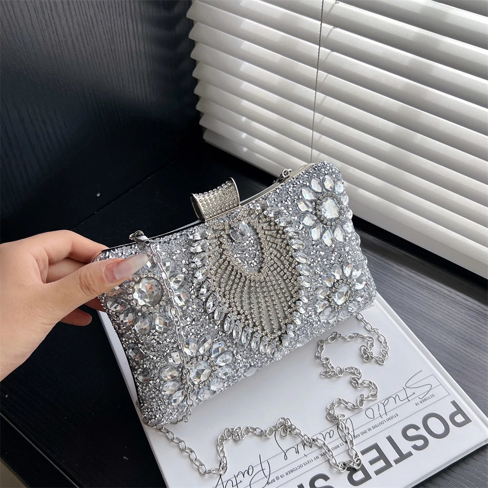 Silver rhinestone evening clutch with a chain strap resting on a white surface.