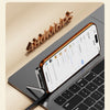 A close-up of a smartphone displaying a file transfer screen, resting on a laptop keyboard with a foldable cable nearby.