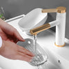 A hand is pouring water from a gold and white faucet into a leaf-shaped suction cup soap dish.