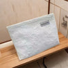 A white canvas storage pouch for chargers is displayed on a wooden shelf.