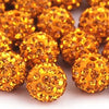 A pile of small, round, golden-yellow crystal clay beads for DIY jewelry and craft projects.