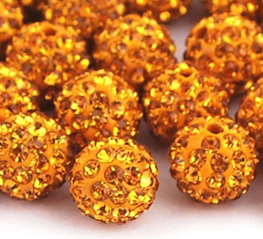 A pile of small, round, golden-yellow crystal clay beads for DIY jewelry and craft projects.