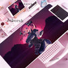 A pink-haired anime character illustration on a purple desk mat with various electronic devices and accessories.