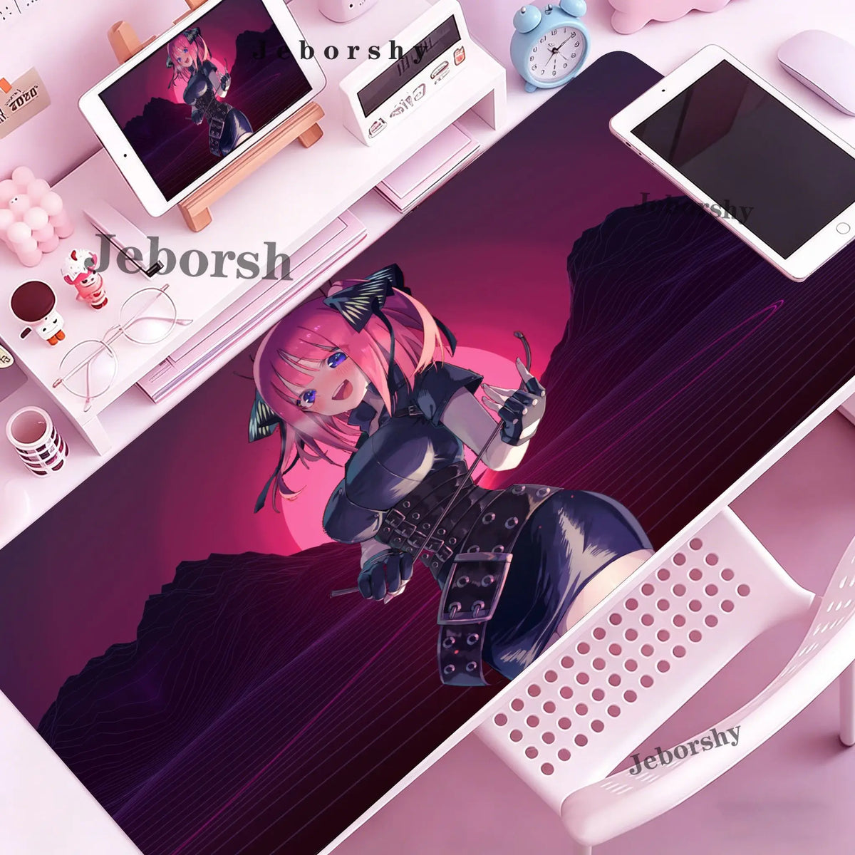 A pink-haired anime character illustration on a purple desk mat with various electronic devices and accessories.