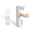 A white touchless automatic soap dispenser with a pump mechanism and USB charging cable shown next to a hand.