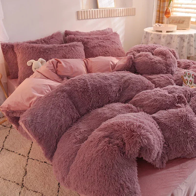 A pile of fluffy mauve mink velvet bedding, including a duvet cover and sheets, displayed on a bed.