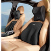 A black memory foam car headrest and lumbar support cushion installed in a tan leather car seat.