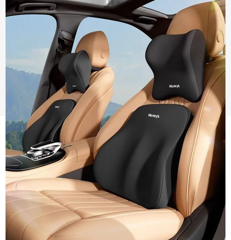 A black memory foam car headrest and lumbar support cushion installed in a tan leather car seat.