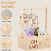 A wooden baby shower crate with a rainbow design and hangers displaying baby clothes.