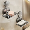 A wall-mounted soap dish with a suction cup dispenser and drain, featuring a silver metal finish.