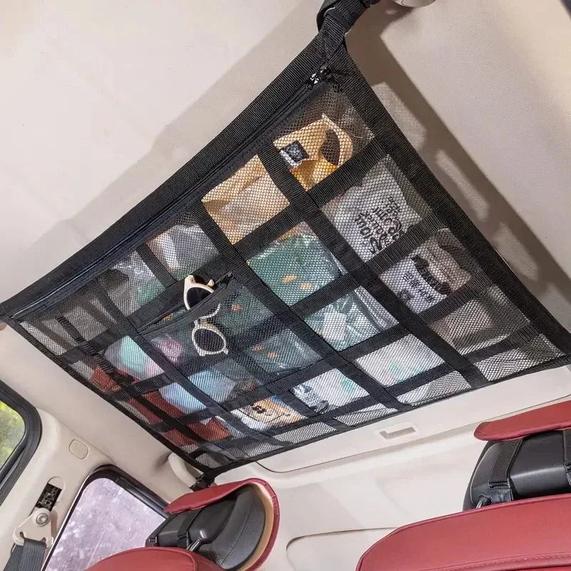 A black ceiling cargo net organizer is installed in a vehicle, featuring mesh pockets for storage.