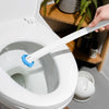 Une main tient une brosse de toilette blanche jetable avec une longue poignée au-dessus d'une cuvette de toilette blanche.
