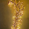 A branch of cherry blossom tree lamp with delicate pink LED lights illuminates a textured yellow wall.
