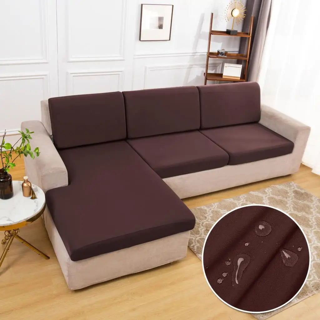 A dark brown waterproof sofa cushion cover with an elastic edge resting on a beige sofa.