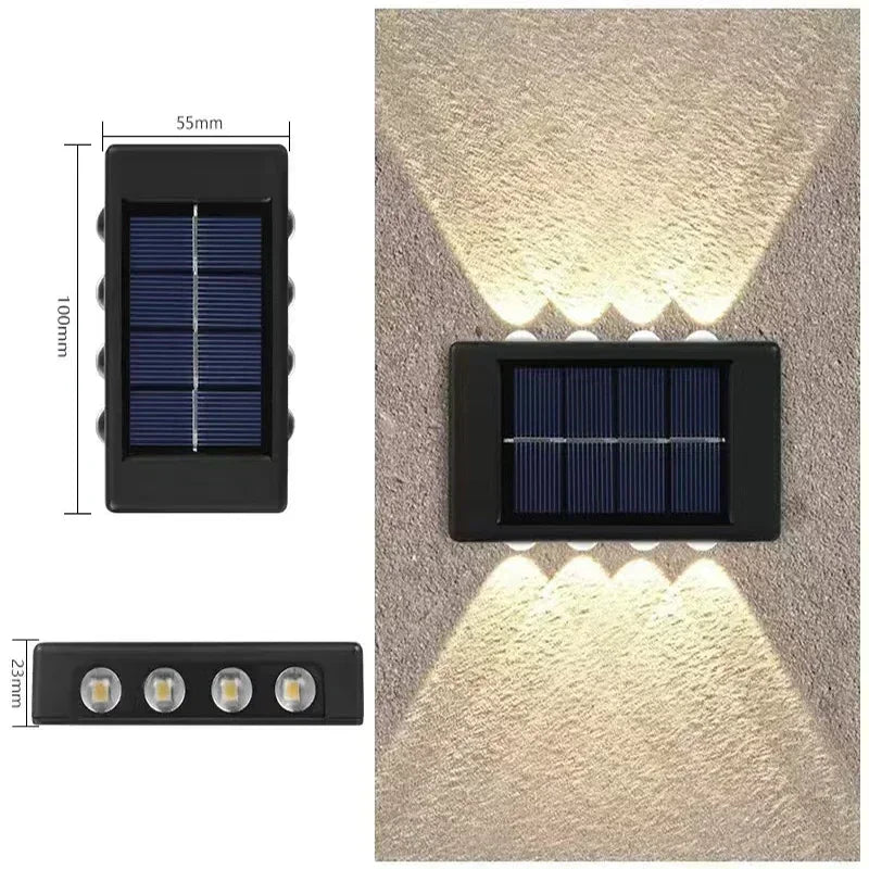 A black solar powered outdoor wall light with an upper and downward illumination pattern mounted on a textured wall.