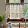 Beige gingham cafe curtain with crochet lace trim hanging in a window.