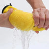 A hand is holding a bright yellow microfiber cleaning towel, which is being rinsed under water.