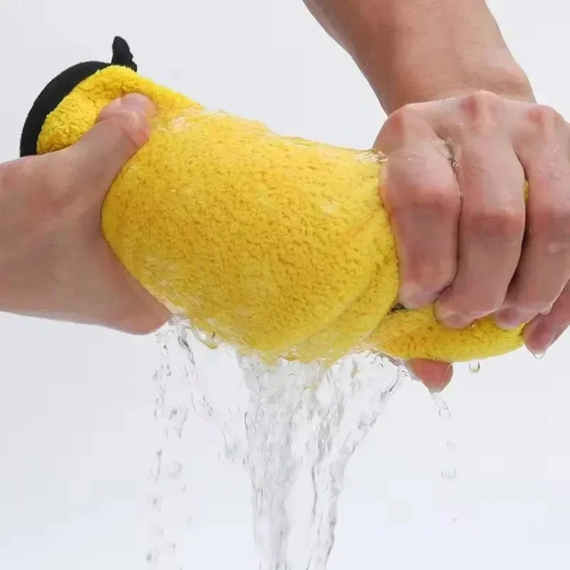 A hand is holding a bright yellow microfiber cleaning towel, which is being rinsed under water.