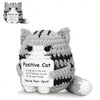 A gray and black knitted cat plush ornament with a tag that reads Positive Cat