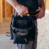 A person is holding a black durable Oxford cloth tool belt with multiple pockets.