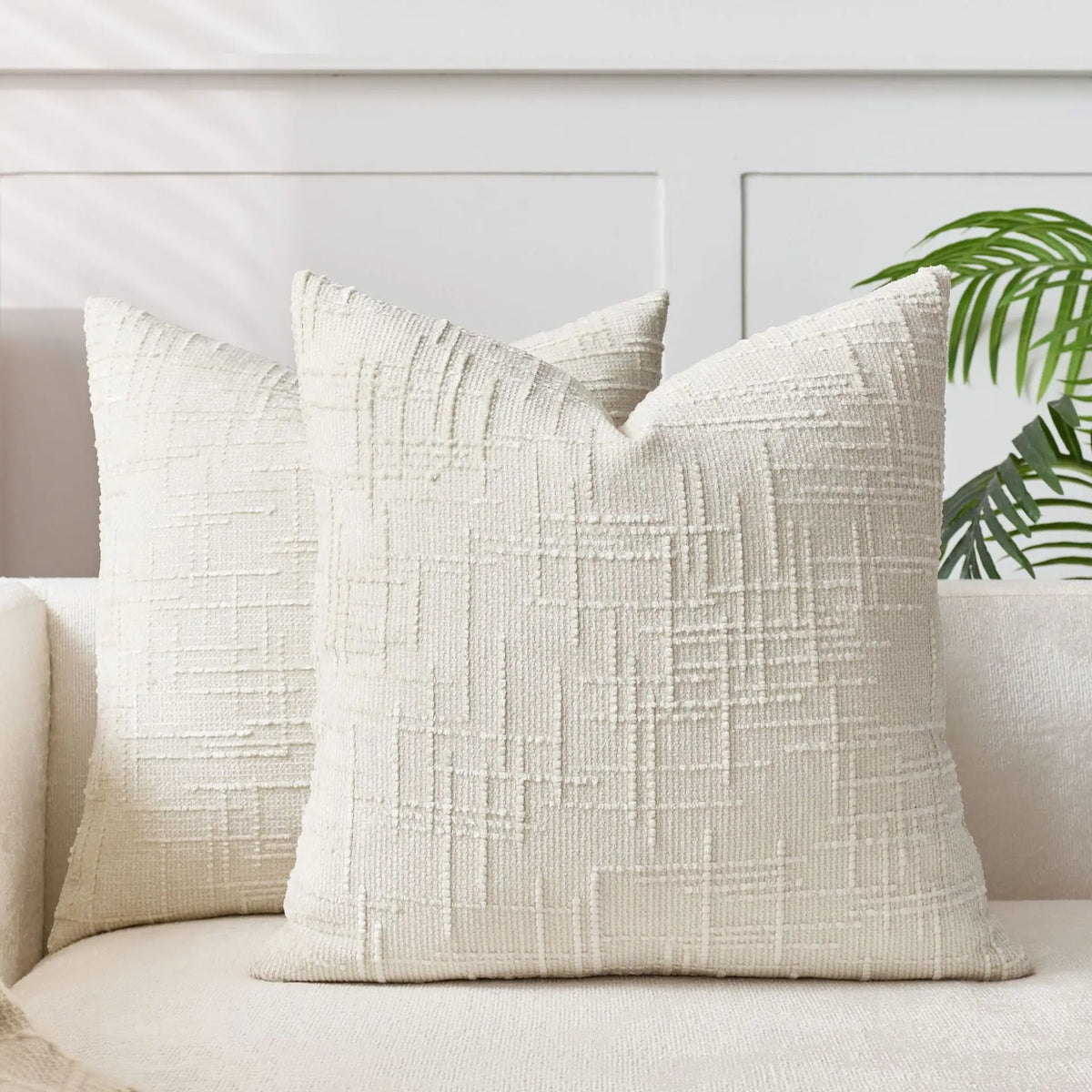 A close-up of a cream handwoven chenille texture cushion cover resting on a light sofa.